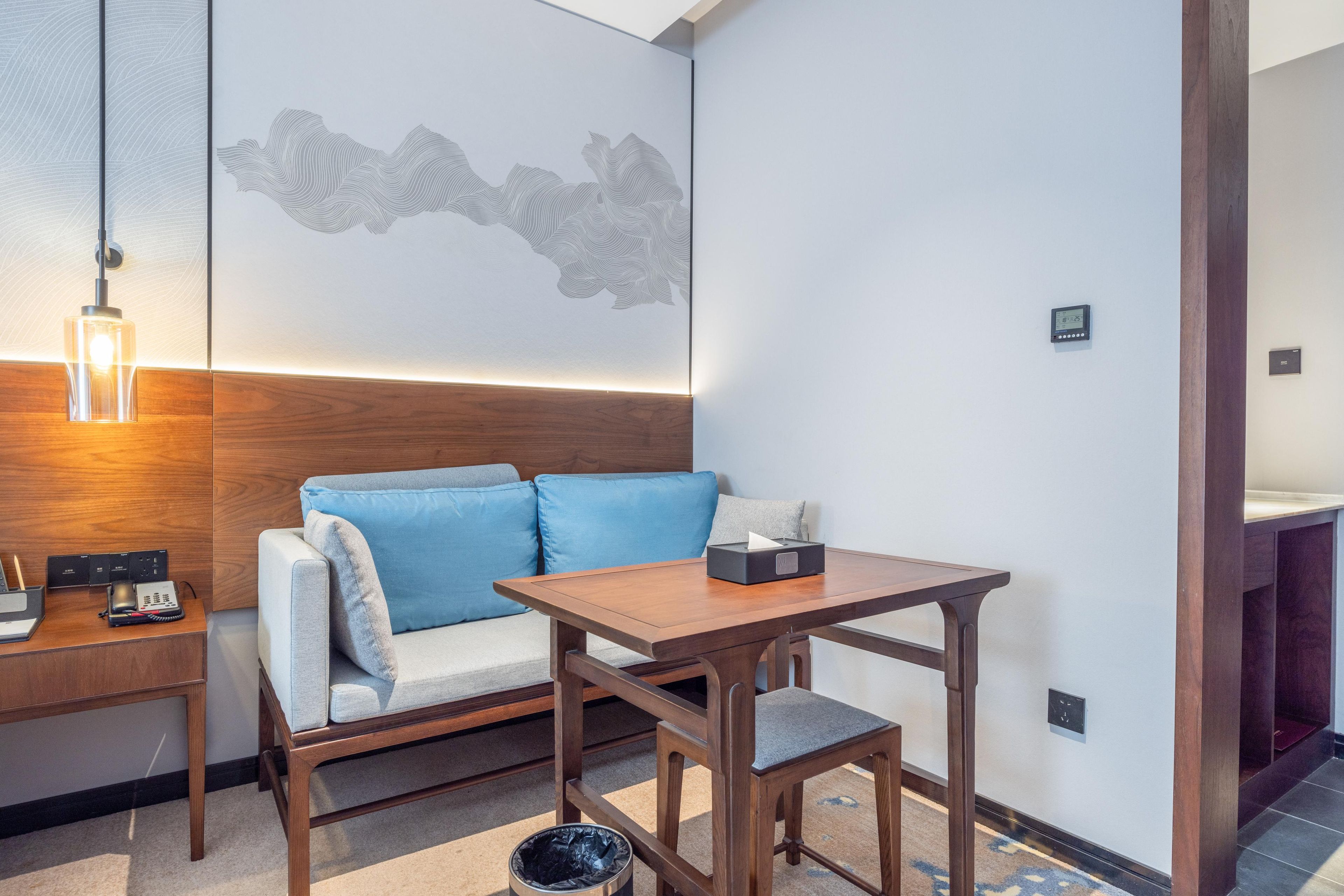 A modern room with a wooden desk, a blue sofa, and a small table with a tissue box.