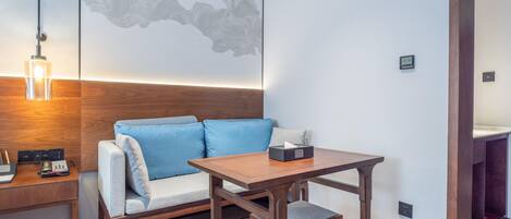 A modern room with a wooden desk, a blue sofa, and a small table with a tissue box.
