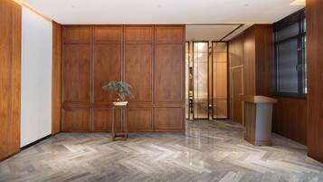 A modern lobby with wooden paneling, a herringbone floor, and a potted plant.