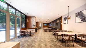 A spacious restaurant with long tables and chairs, large windows, and artwork on the walls. - Madison Hotel Jinan Suncun Chunhui Road (Jinan)