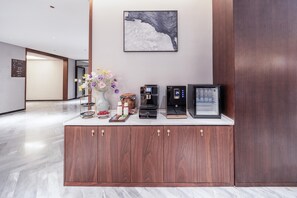 A reception area with a wooden cabinet, a coffee machine, a digital clock, and a framed picture on the wall. - Madison Hotel Jinan Suncun Chunhui Road (Jinan)
