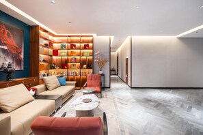A modern living room with a sofa, armchairs, a coffee table, and a bookshelf. - Madison Hotel Jinan Suncun Chunhui Road (Jinan)