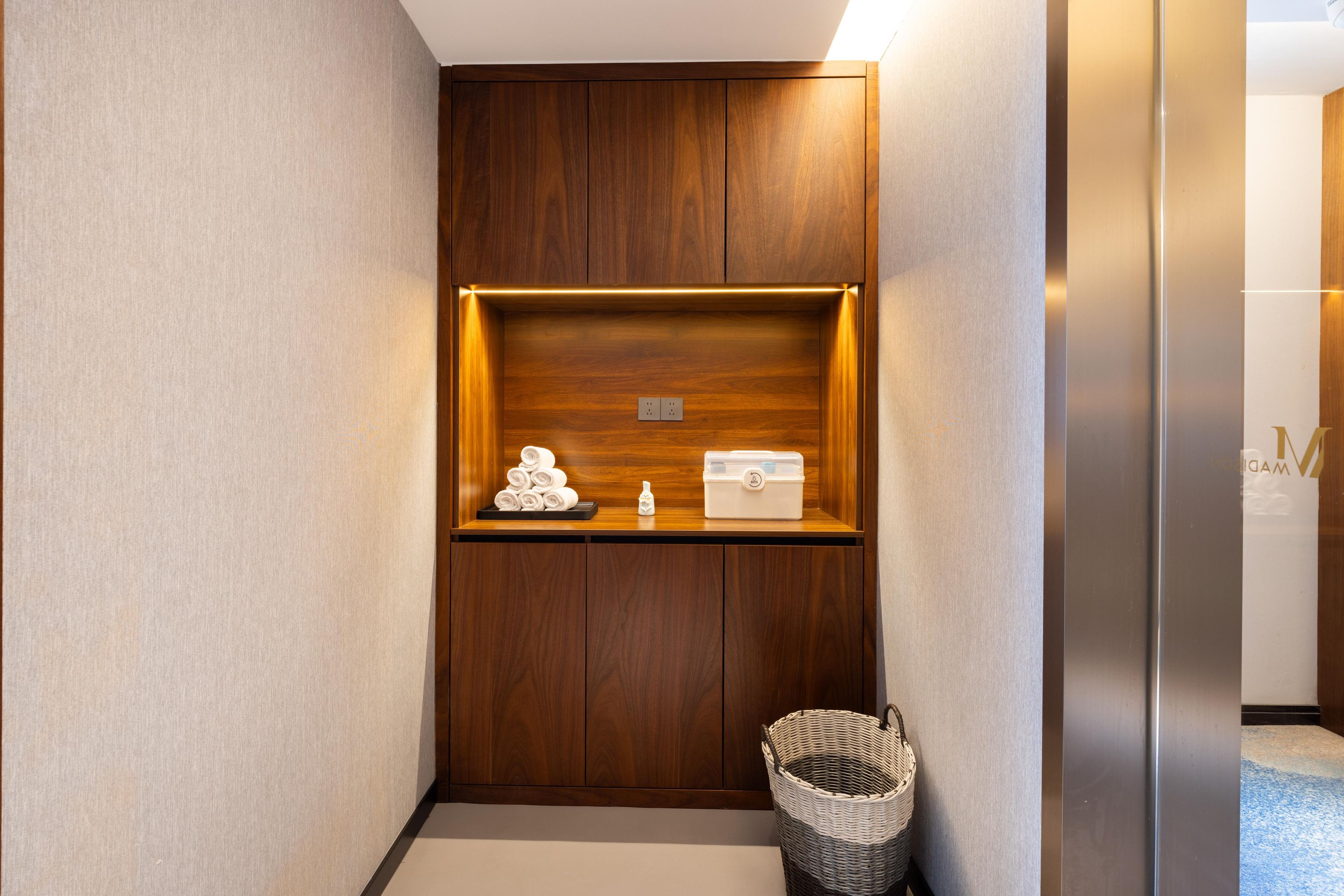 Ein Hotel-Rezeptionsbereich mit einem Holzkabinett, einem kleinen Korb und einer weißen Aufbewahrungsbox.