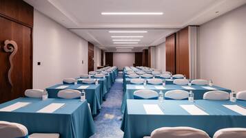 A conference room with rows of tables and chairs, equipped with water bottles and nameplates.