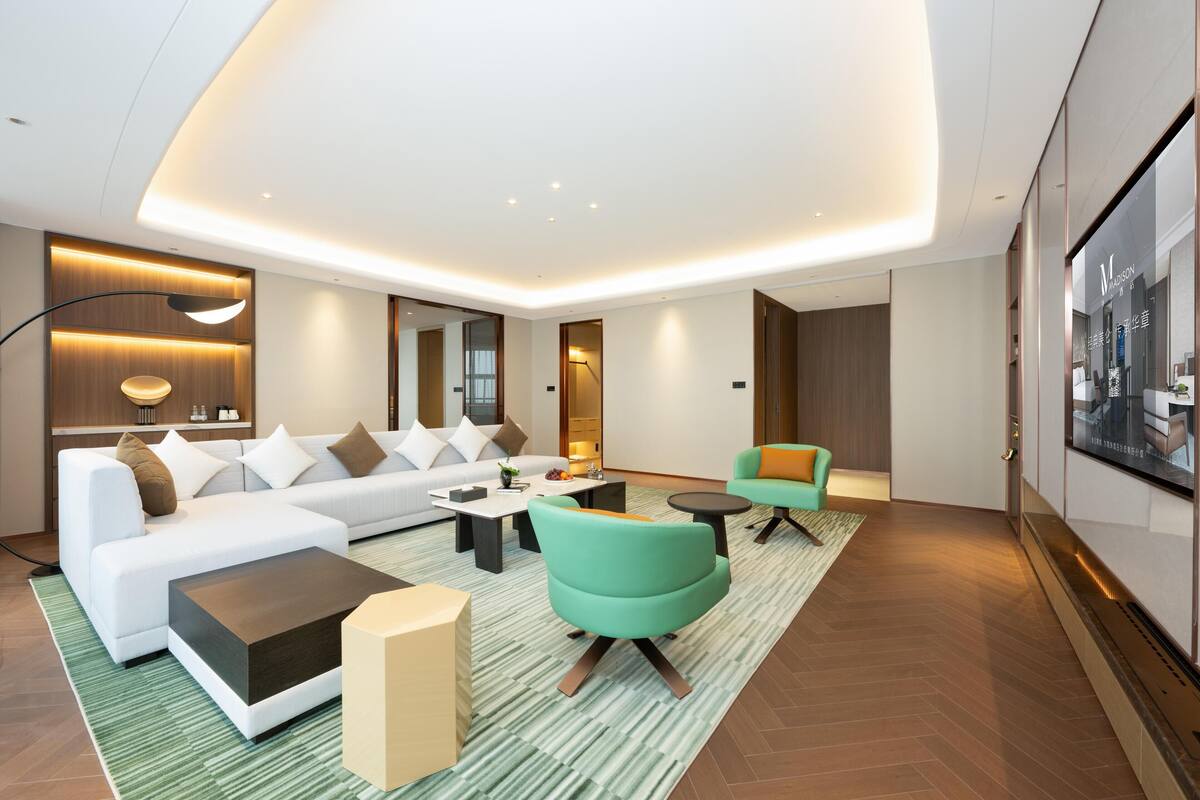 Una sala de estar moderna con un sofá blanco, sillones verdes y una mesa de centro.