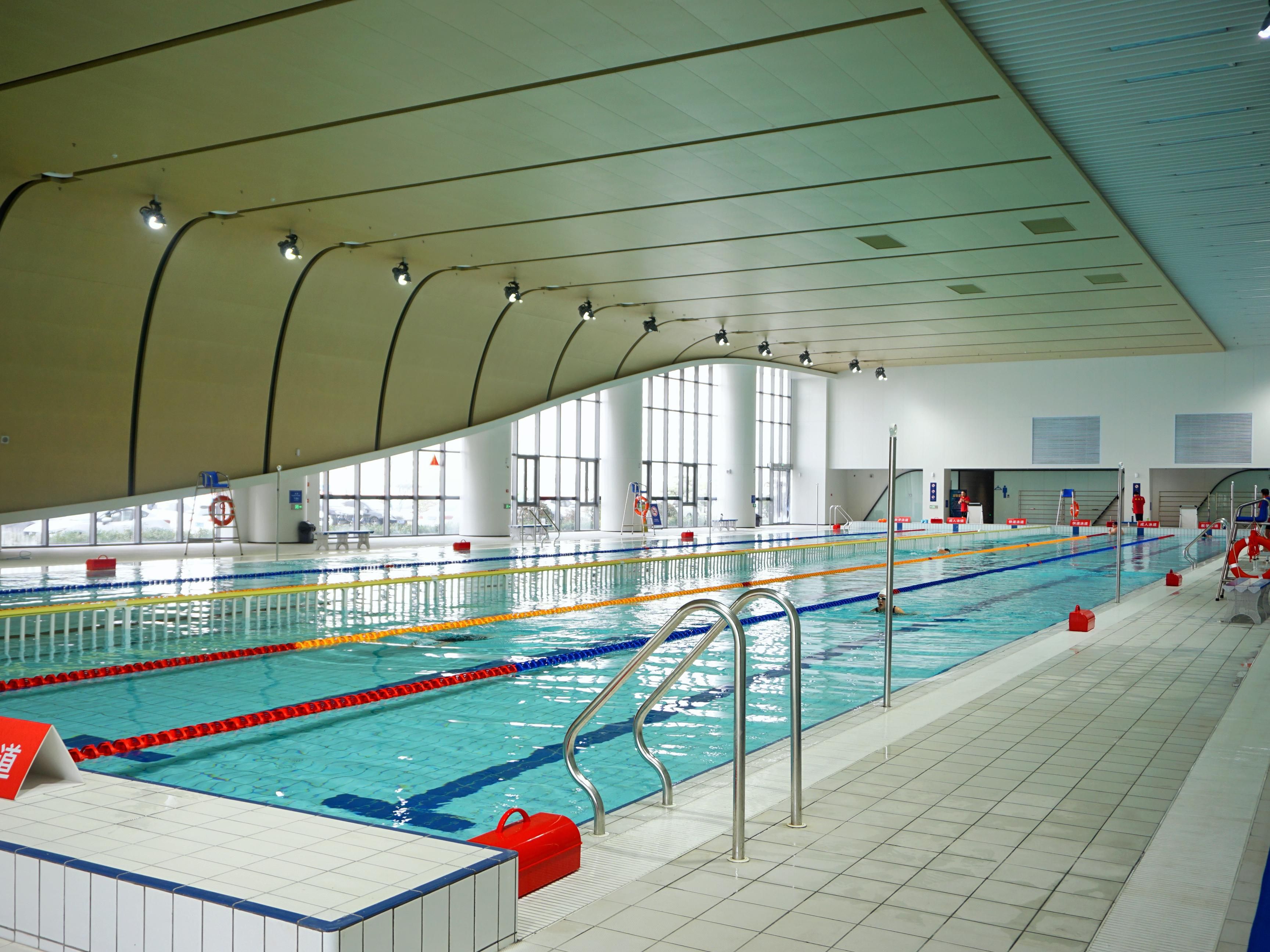 An indoor swimming pool with clear lanes, a lifeguard stand, and a tiled floor.
