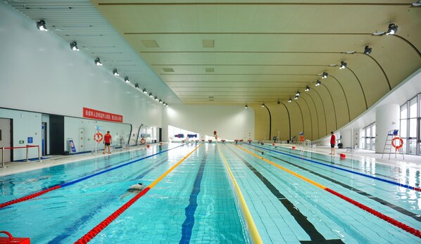 Una piscina interior con varias pistas, equipo de seguridad y boyas salvavidas.