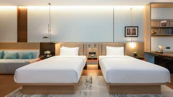 Habitación de hotel con dos camas, un sofá, un escritorio y una estantería.