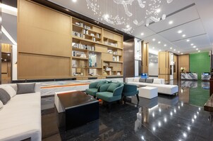 Um lobby moderno com uma grande estante de livros, área de estar e balcão de recepção.
