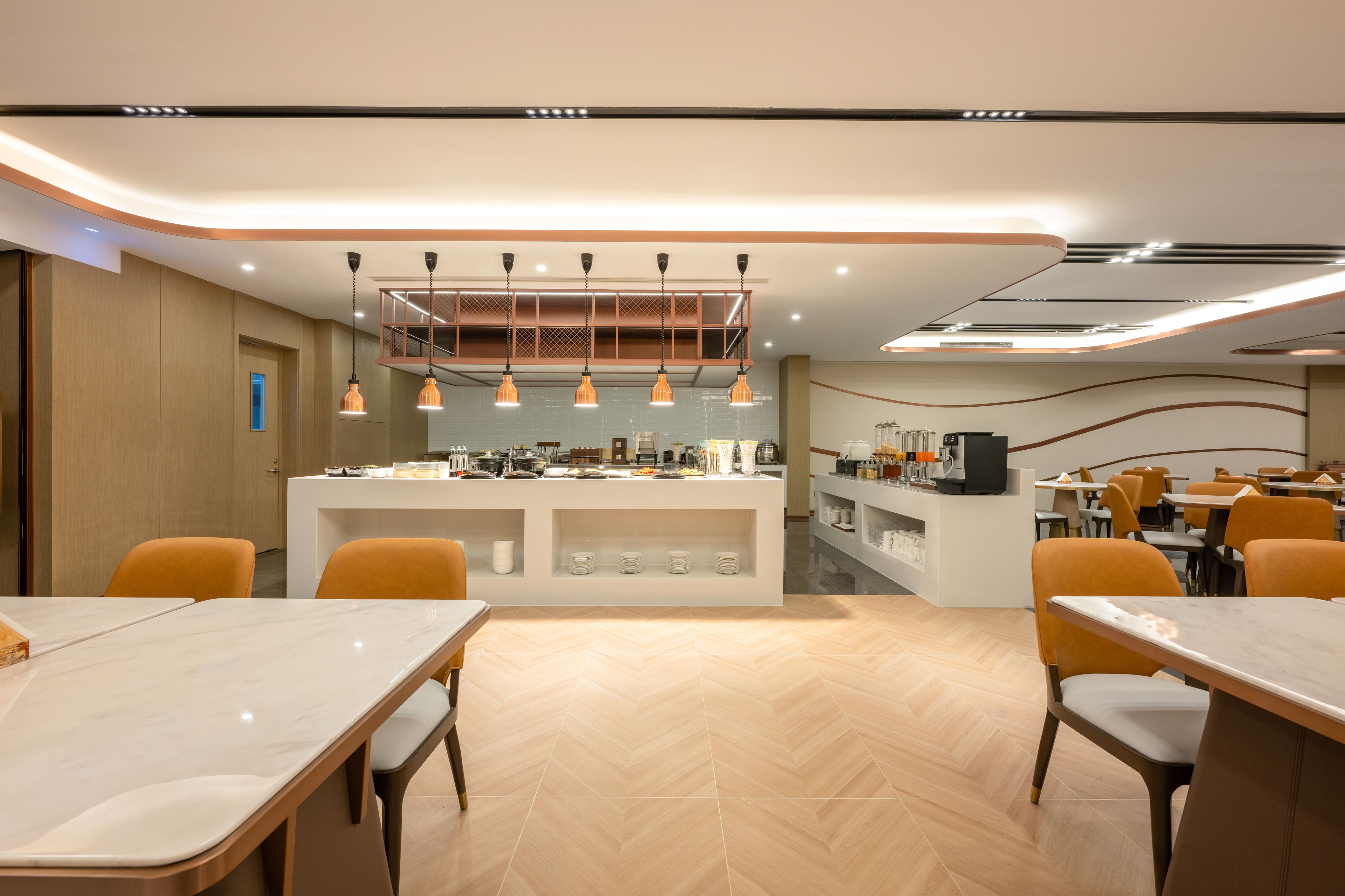 Un área de comedor moderna con una barra central, varias mesas y sillas color naranja.