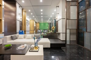 Un moderno vestíbulo de hotel con un sofá blanco, una mesa de centro y una pared verde al fondo.