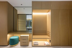 Un baño moderno con tocador de madera, un taburete verde azulado y un espejo.