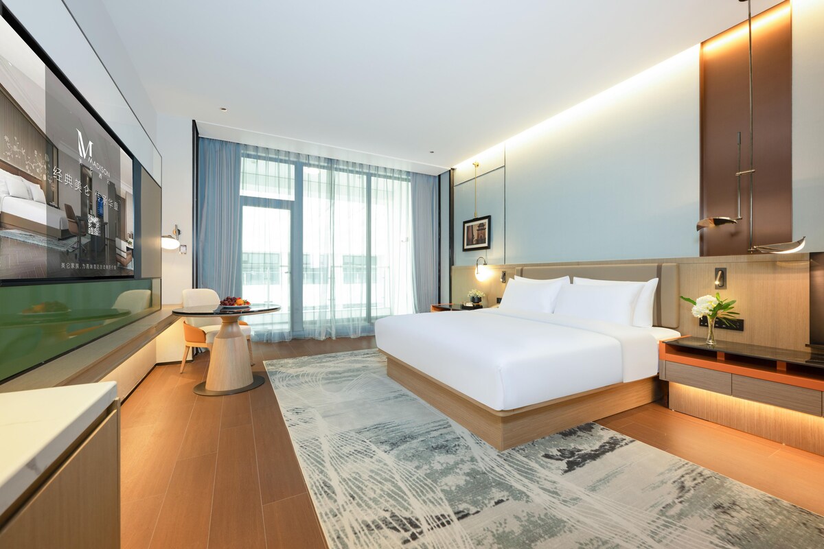 A modern hotel room with a large bed, a desk, and a television.