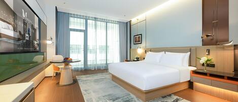 A modern hotel room with a large bed, a desk, and a television.