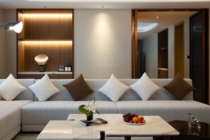 Una sala de estar moderna con un sofá, una mesita de centro con fruta y una lámpara fijada a la pared.