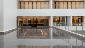 Ένας ευρύχωρος χώρος υποδοχής με ένα γυαλιστερό δάπεδο, έναν διώροφο κεντρικό χώρο και ένα γυάλινο κιγκλίδωμα που προσφέρει θέα στο χαμηλότερο επίπεδο.