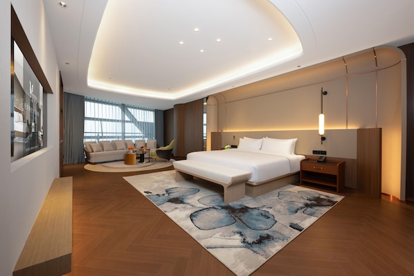Una habitación de hotel moderna con una cama grande, un sofá, un escritorio y vistas a la ciudad.