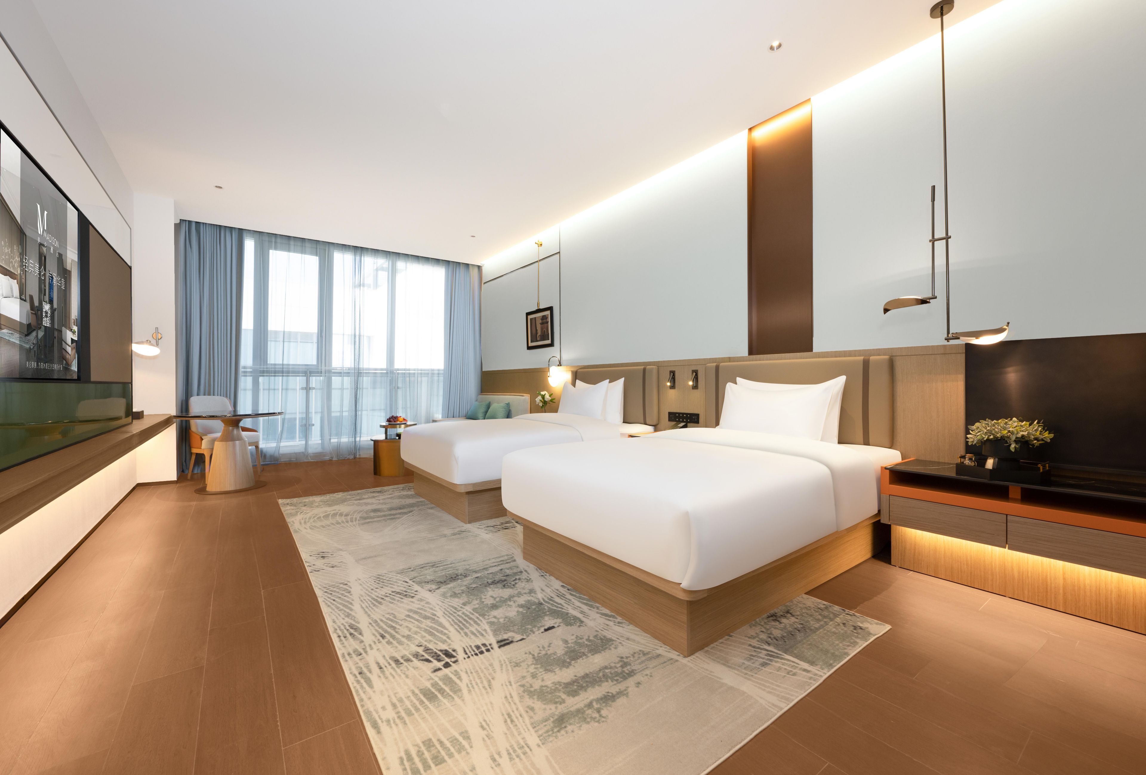 A modern hotel room with two beds, a large window with curtains, a flat-screen TV, and a wooden floor.