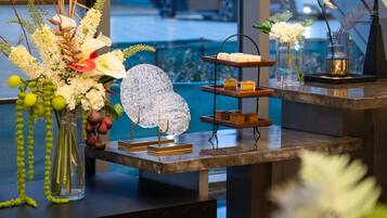 Un mostrador de recepción con un florero, una escultura de vidrio decorativa y una bandeja escalonada con aperitivos.