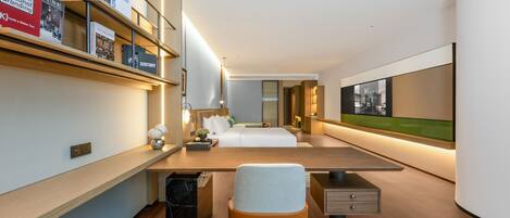 Una habitación de hotel moderna con una cama grande, un escritorio, una silla y una estantería llena de libros.