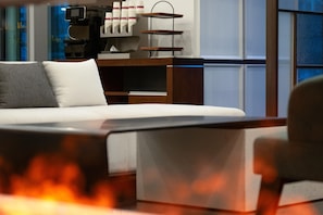 Habitación de hotel moderna con cama, escritorio y silla. Pequeña mesa con tazas y bandeja. La habitación tiene ventana con vista a la ciudad.
