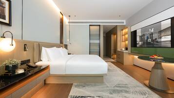 A modern hotel room with a large bed, bedside table, and a television.