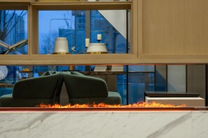 Una sala moderna con chimenea, un sofá verde y vistas de la ciudad a través de amplios ventanales.