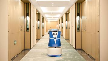 A hallway with a blue and white robot in the center, wooden walls, and a marble floor.