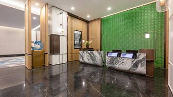 A modern reception area with a marble counter, a green textured wall, and a polished floor.