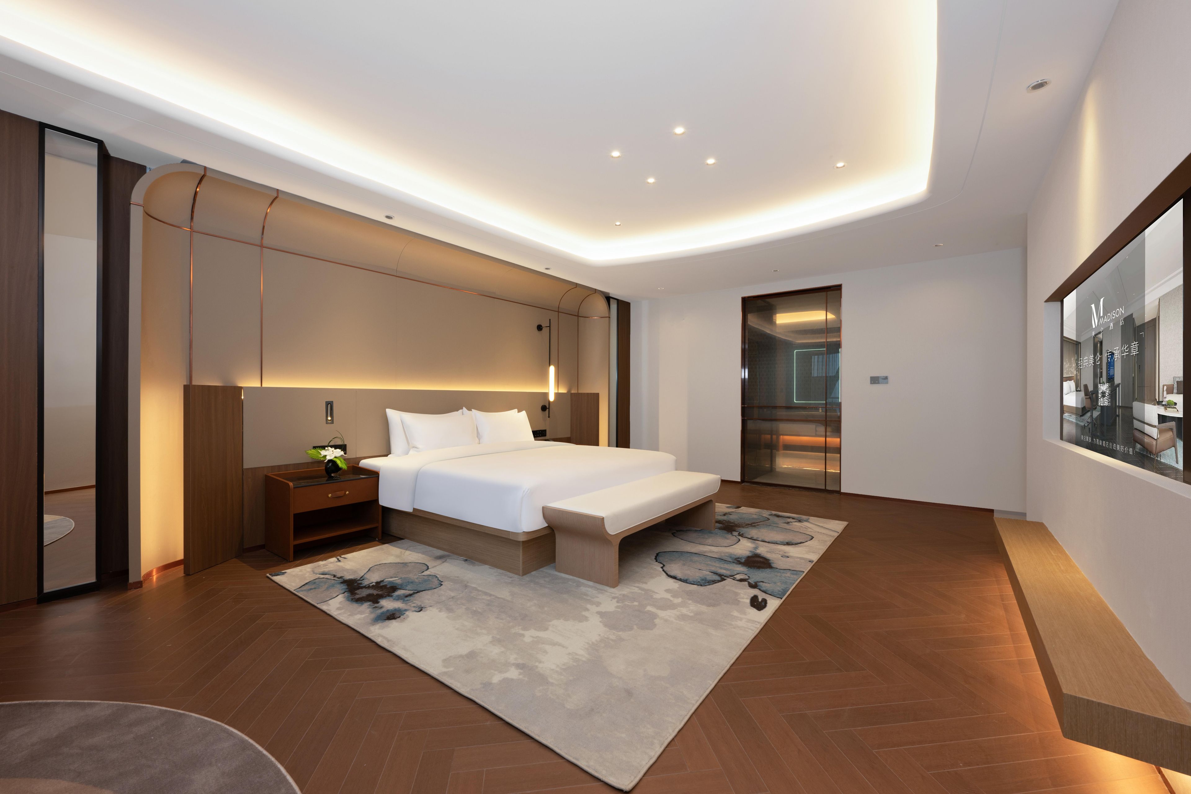 A modern bedroom with a large bed, bedside tables, a nightstand, and a built-in bench.