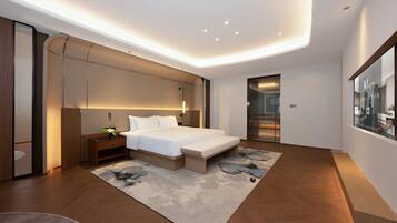 A modern bedroom with a large bed, bedside tables, a nightstand, and a built-in bench.