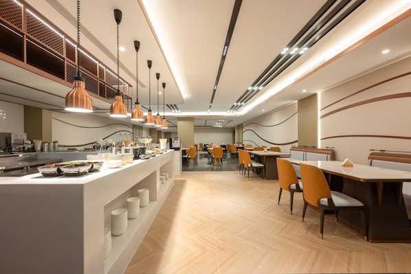 Un comedor moderno con una isla central, diversas opciones de asientos e iluminación colgante.