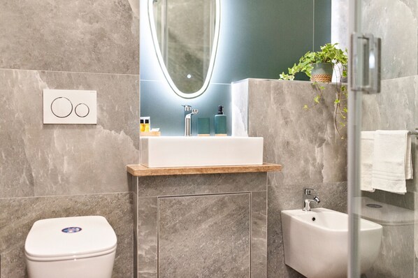 Une salle de bain moderne avec un lavabo blanc, un bidet et des toilettes.