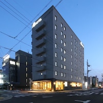 Un hotel de varios pisos con diseño moderno, que cuenta con un llamativo letrero 'HOTEL' en la fachada.