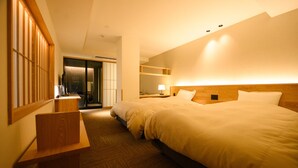 A hotel room with two beds, a wooden desk, a mirror, and a sliding door leading to a bathroom. - Yukawa Terrace (Kusatsu)