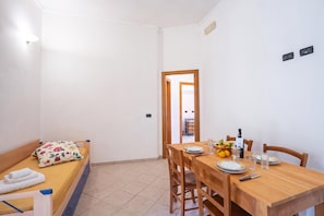 Habitación compacta con cama, mesa de comedor para dos personas y pequeña cocina.