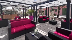An outdoor seating area with a covered patio, red and black furniture, and a potted plant. - Borgo Primizia T1 Pool and Sea, Otranto, Italy (Otranto)