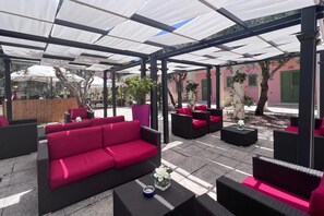 An outdoor seating area with a covered patio, red and black furniture, and a potted plant. - Borgo Primizia T1 Pool and Sea, Otranto, Italy (Otranto)
