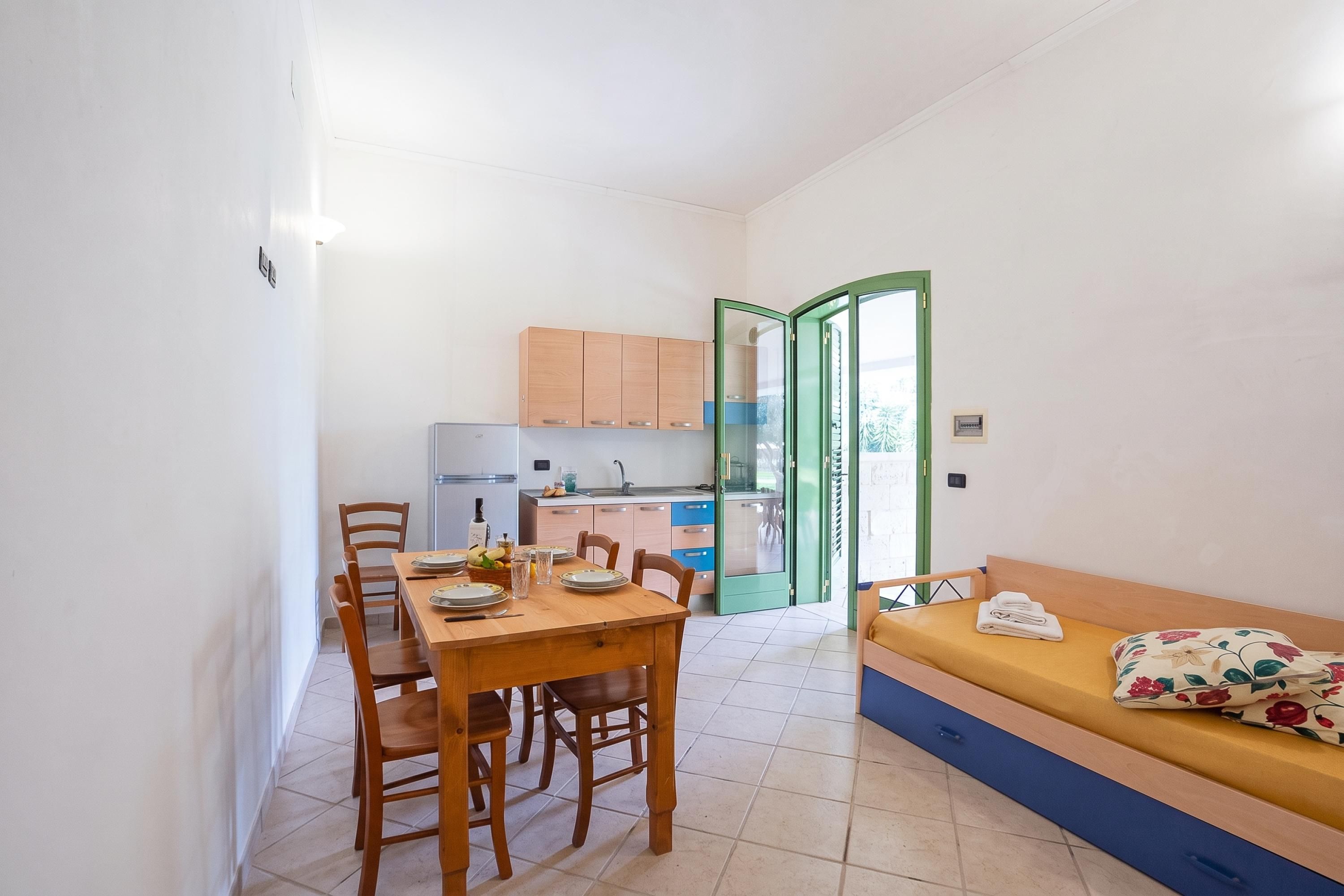 Un espacio habitable funcional con zona de comedor, kitchenette y sofá.