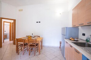 A compact kitchen with a dining table, chairs, a refrigerator, and a sink. - Borgo Primizia T1 Pool and Sea, Otranto, Italy (Otranto)