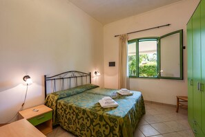 A bedroom with a bed, bedside tables, a window with curtains, and a green wardrobe.