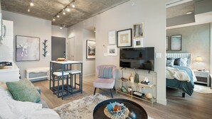 A modern living room with a sofa, a coffee table, a TV, and a dining area with a chair and table.