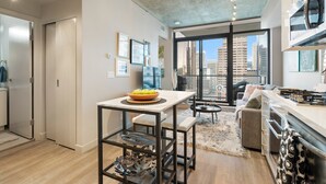 A modern kitchen with a dining area, large windows, and a city view.
