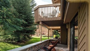 Un espace extérieur aménagé, abrité et doté de murs en pierre, de mobilier en bois et offrant une vue sur un bâtiment avec un balcon.