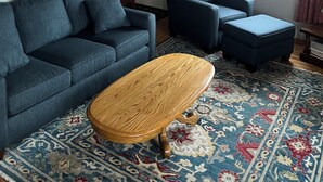 Una sala de estar con un sofá azul, un sillón a juego, una mesa de centro de madera y un tapete estampado.