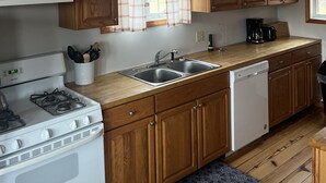 Una cocina con armarios de madera, una estufa blanca, un fregadero y una cafetera.