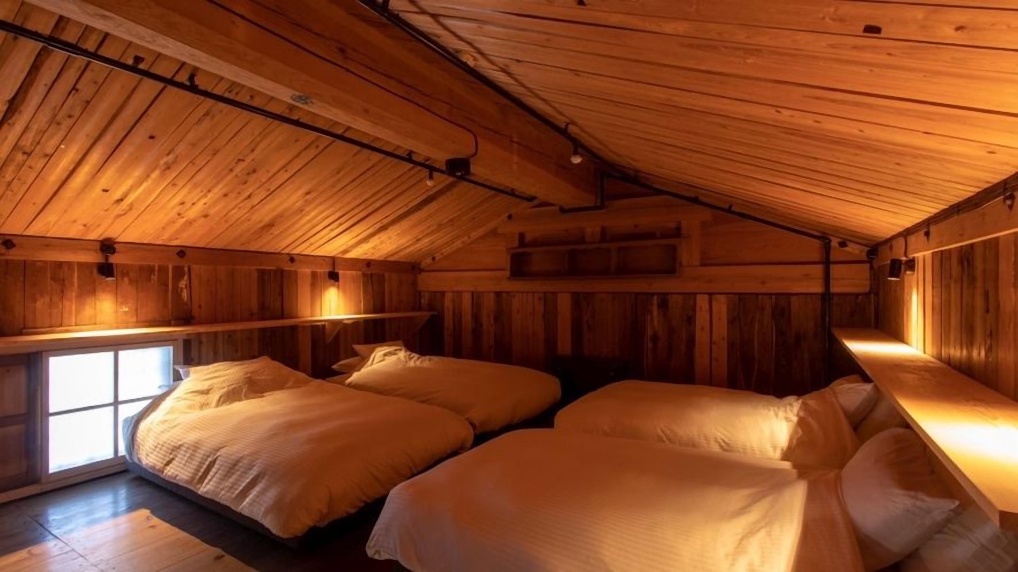 Una cabaña con dos camas, paredes de madera y techo inclinado.