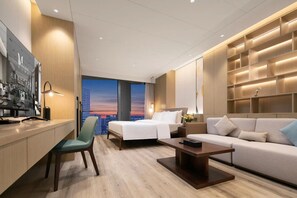 Een moderne hotelkamer met uitzicht op de stad, een bureau, een bank en een bed.