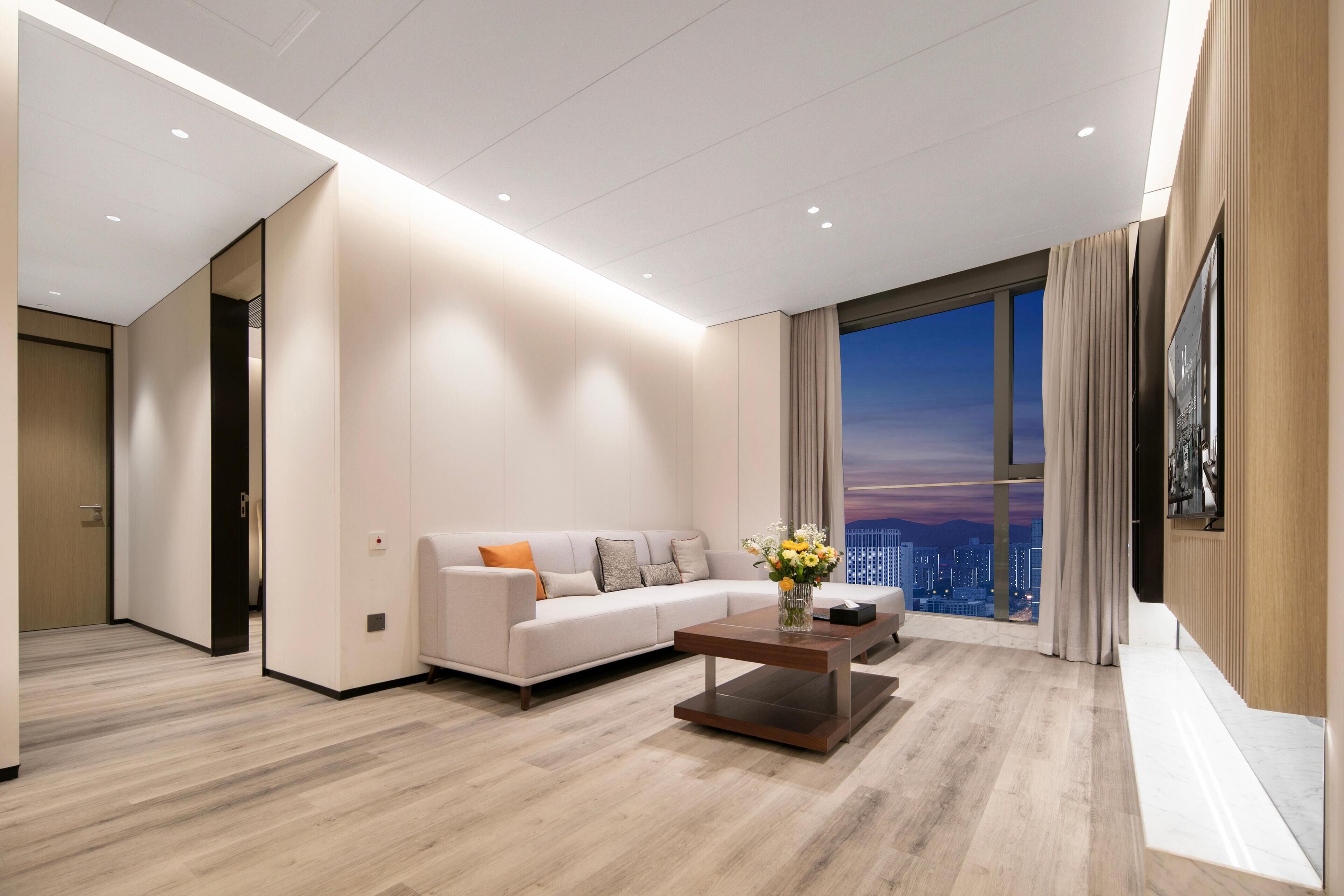 Uma sala de estar moderna com sofá, mesa de centro e uma grande janela com vista para a cidade.