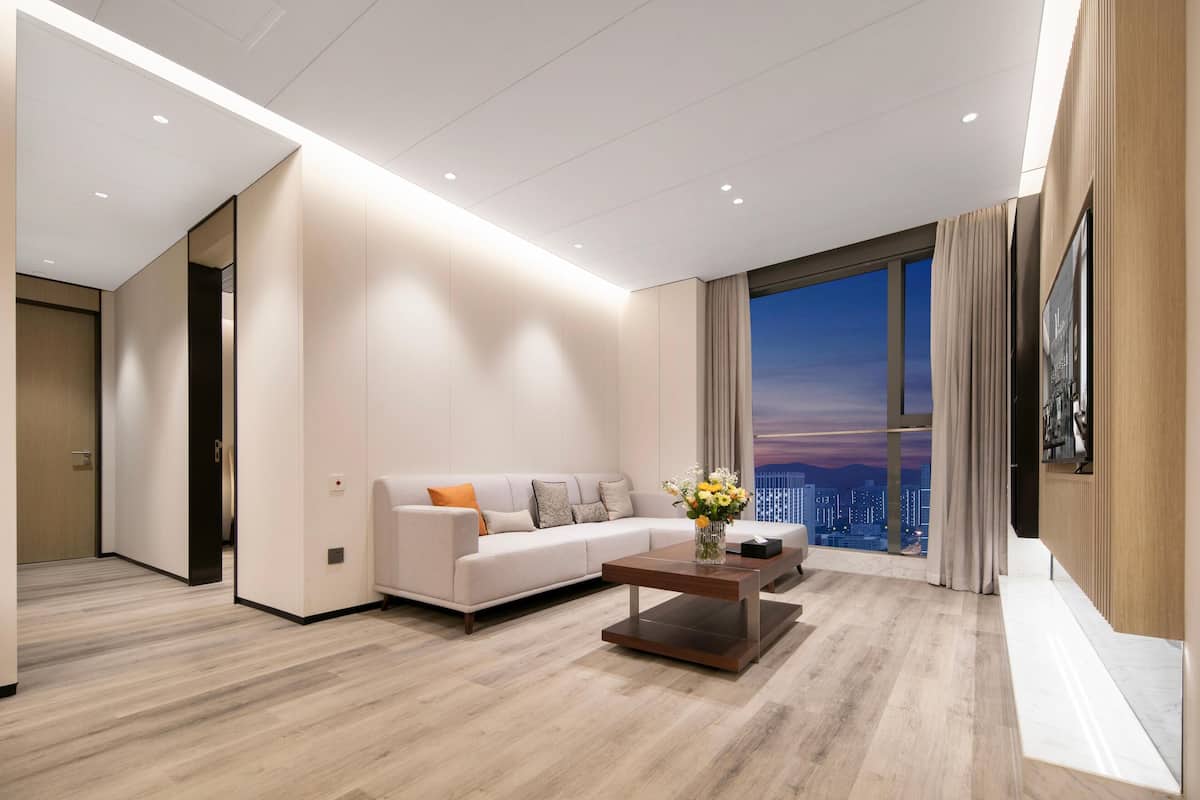 Ein modernes Wohnzimmer mit einer Couch, einem Couchtisch und einem großen Fenster mit Blick auf die Stadt.